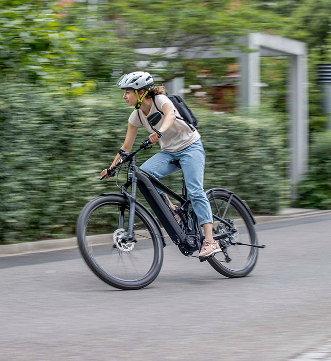 Conduite en ville avec un vélo électrique SUV ATV C de Bergstrom : dynamisme et style réunis Une femme sur un SUV ATV C E-Bike de Bergstrom roule de manière dynamique dans un environnement urbain, en mettant l'accent sur la vitesse et l'agilité.