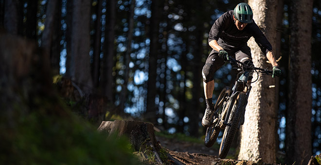 Ton vélo électrique de trail suisse : Bergstrom XCV 7 Un trail rider saute des obstacles en forêt avec son vélo électrique.