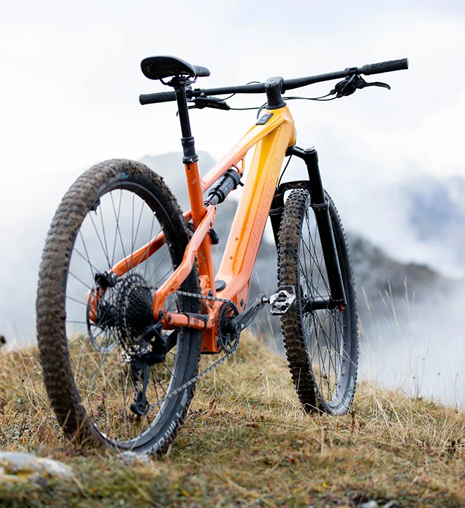 Bergstrom Flow: Erlebe den Flow Bergstrom Flow E-Mountainbike in orange von hinten am Berg.