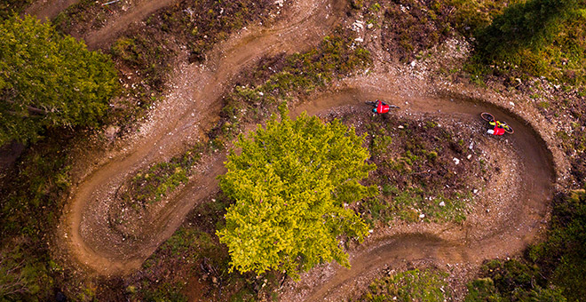 Ton vélo électrique de trail suisse : Bergstrom XCV 7 Deux personnes portant un maillot rouge parcourent le Flow Trail sur des VTT électriques Bergstrom.