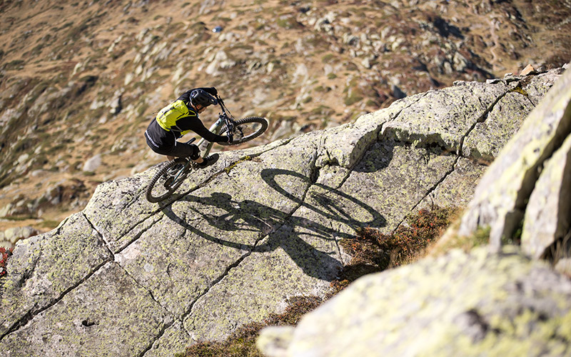 Bergstrom: Abenteuer pur am Aletschgletscher. Mountainbiker meistert einen anspruchsvollen Trail auf einem Bergstrom E-Mountainbike vor der Kulisse des Aletschgletschers.