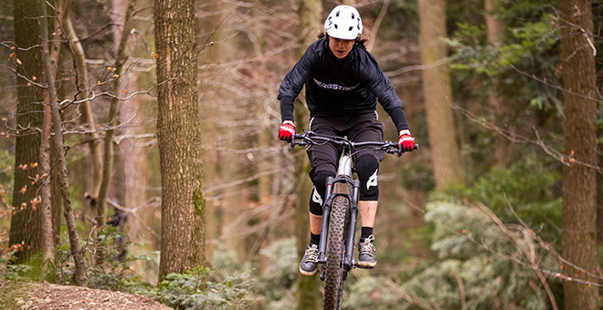 Ton vélo électrique de trail suisse : Bergstrom XCV 7 Personne portant une veste noire sur un vélo électrique Bergstrom XCV 7 Trail dans la forêt.